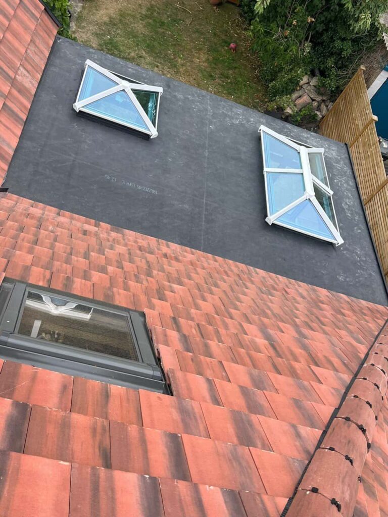 This is a photo taken from the roof ridge looking down a tiled pitched roof on to a flat roof. Works carried out by Liphook Roofing Repairs